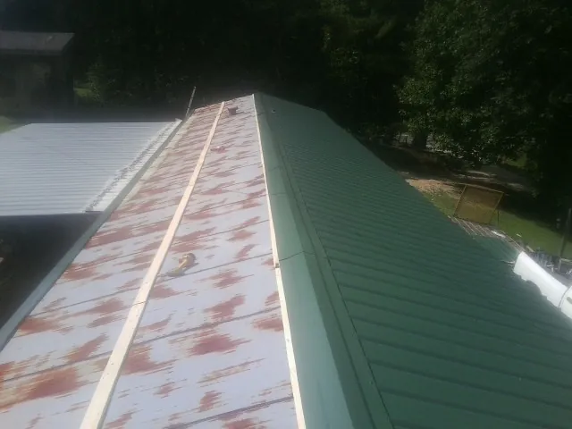 Old rusted panels beside newly installed green metal roofing — Wind Damage Roof Repair by Roofing Brothers in Nashotah