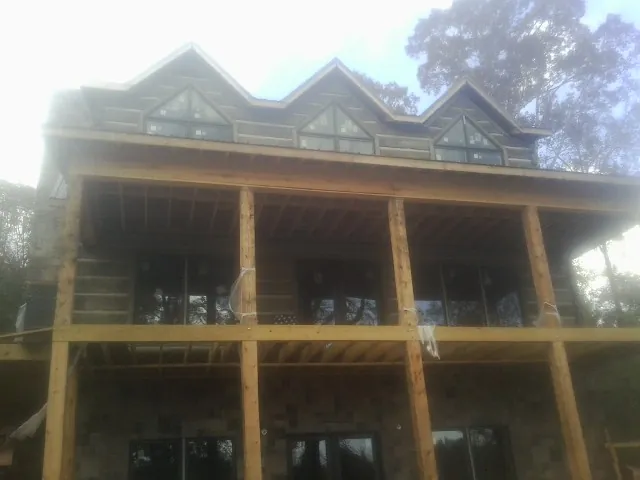 Dormers and porch framing on a large log home under construction — Roof Coating work by our crew in Nashotah