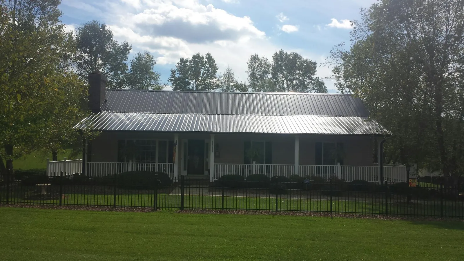 Gray metal roof on a brick ranch with a full width front porch — Gutter Guard Installation work by our crew in Nashotah