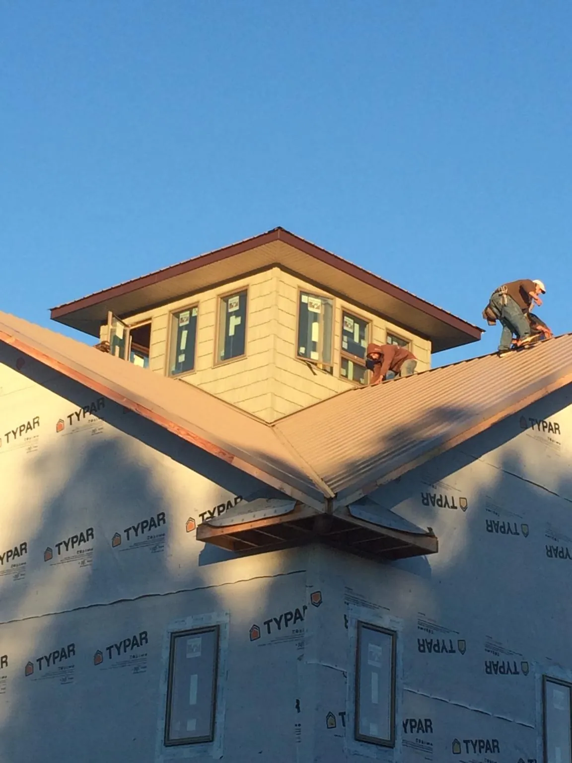Roofers working around a rooftop cupola on a new metal roof at sunset — Roof Waterproofing in Nashotah by Roofing Brothers